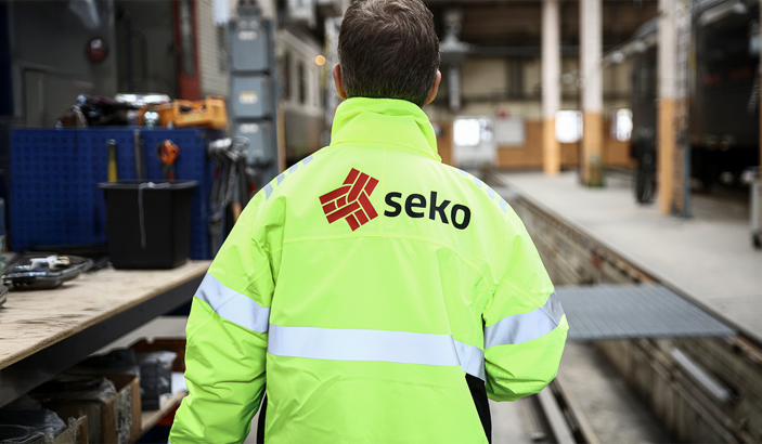 En person fotad bakifrån på arbetsplats, han har en Seko-jacka på sig.